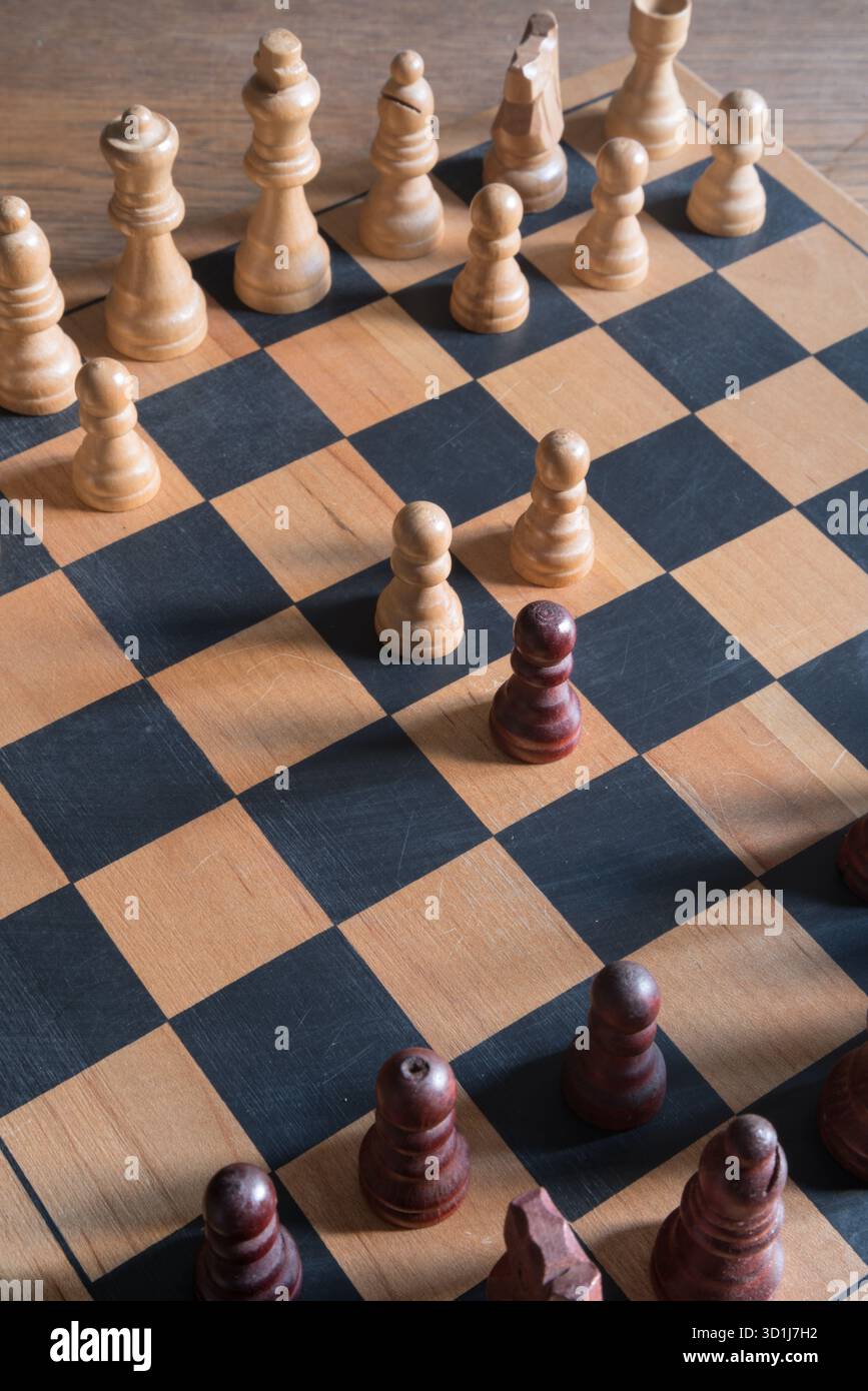 Holzschachbrett mit hellen und dunklen Schachfiguren in einer Mitte des Spiels, die Strategie und intellektuelle Herausforderung hervorheben. Stockfoto