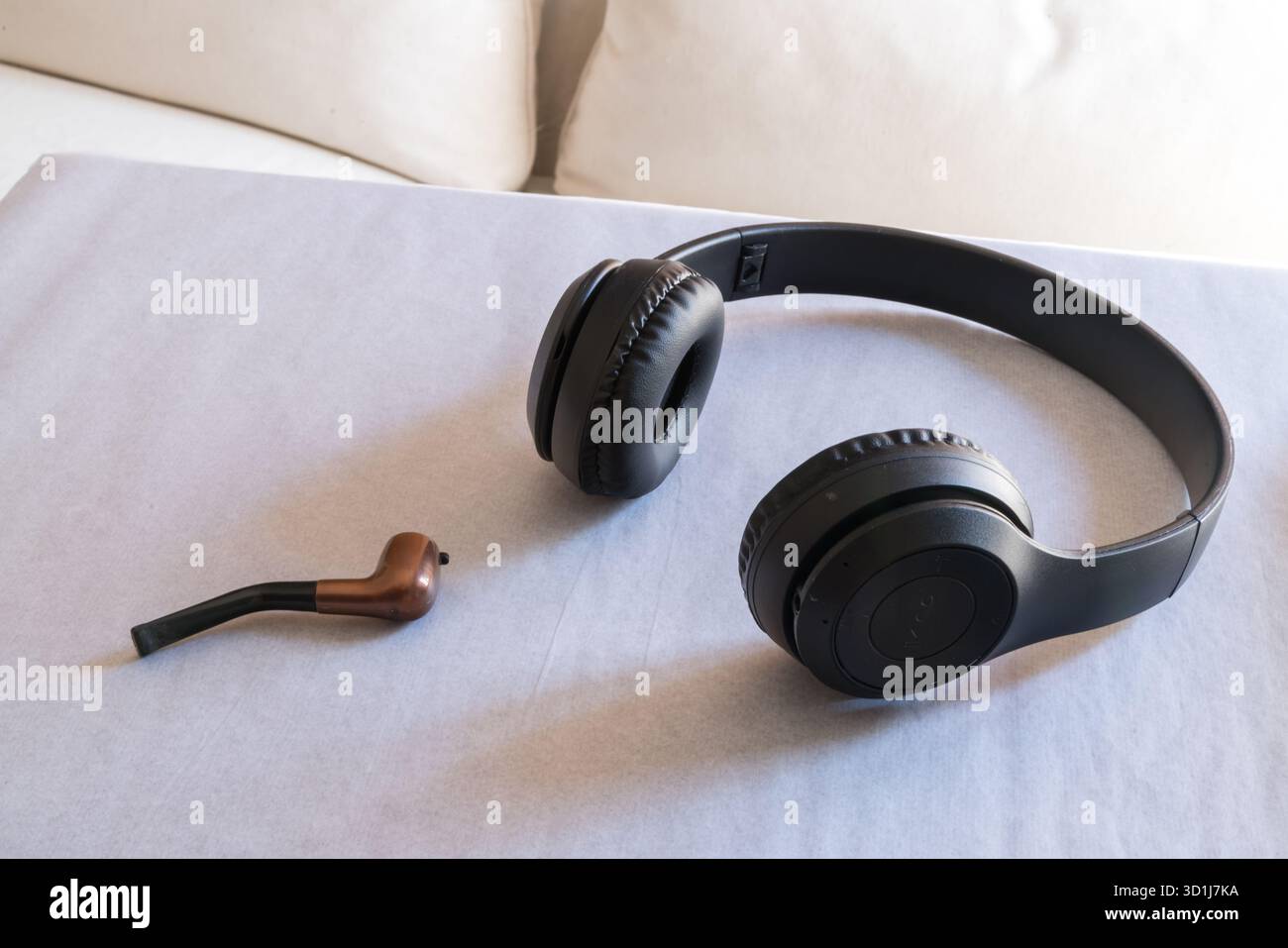 Kabellose Kopfhörer und eine mintfarbene Rauchpfeife auf weißem Papier, die auf Nichtraucher-Tabak hindeutet Stockfoto