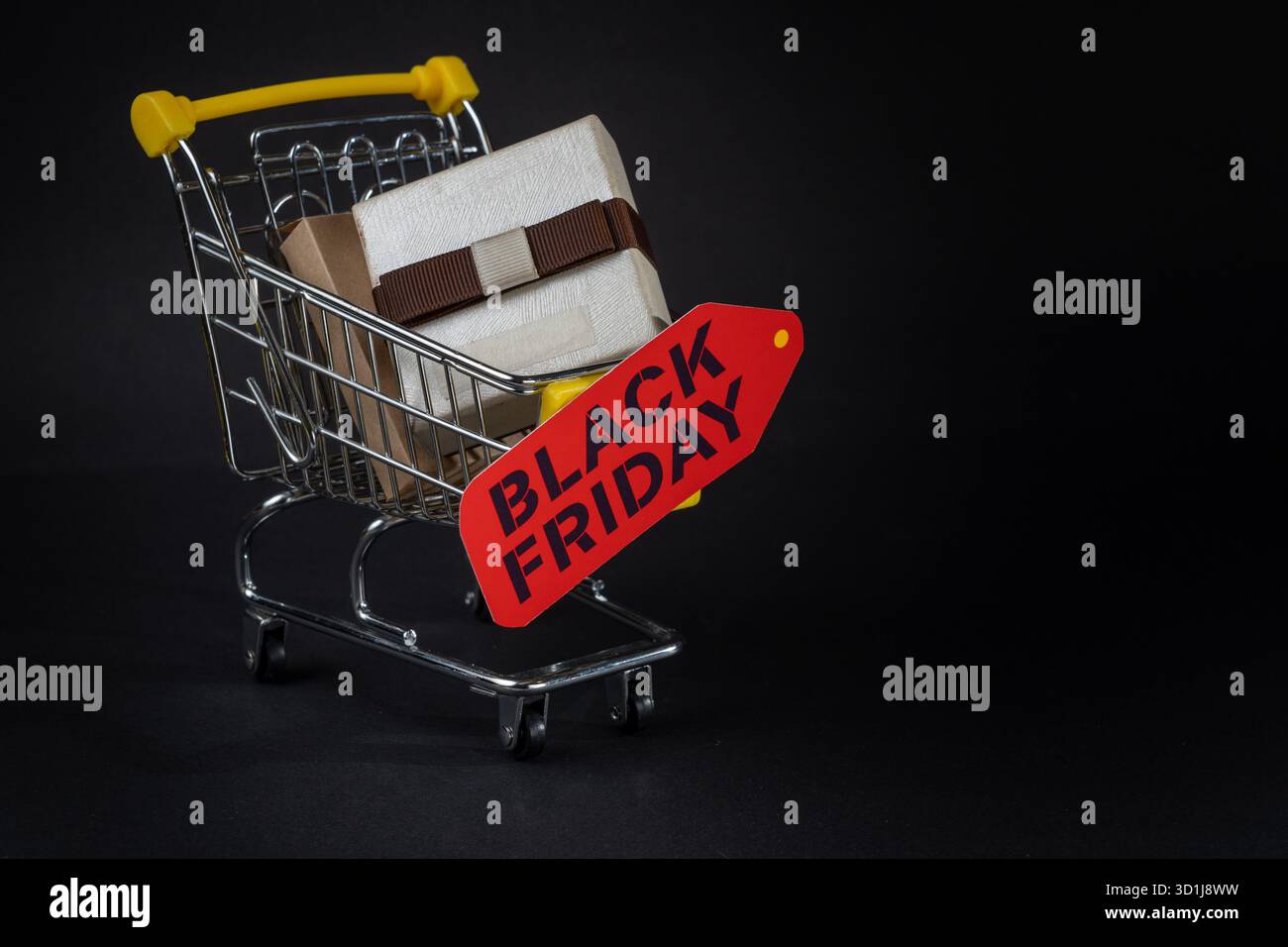 Miniatur-Einkaufswagen mit eingepackten Geschenken und einem schwarzen freitag-Anhänger, der den Einkaufsbummel während des Verkaufs symbolisiert Stockfoto