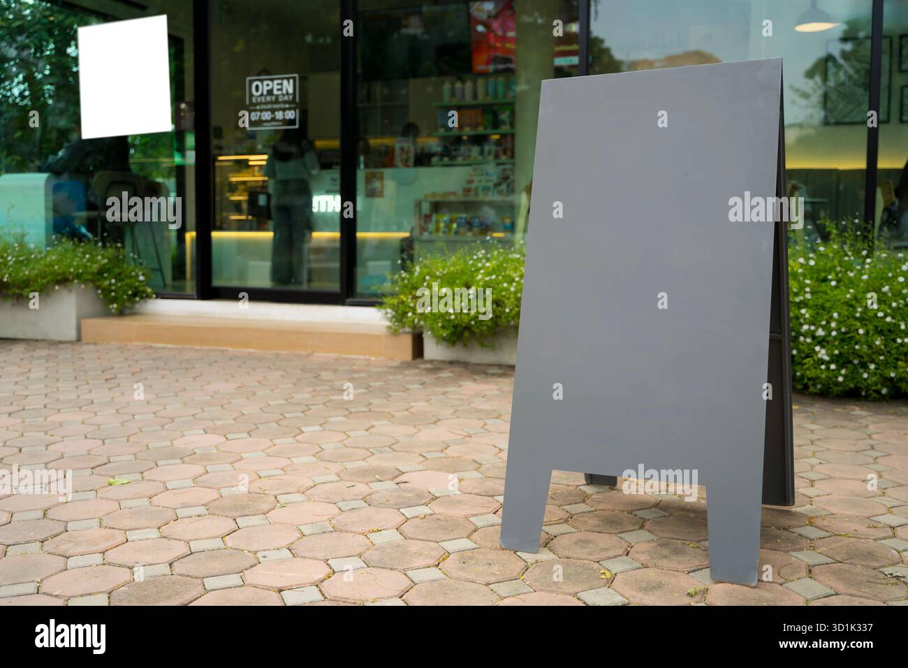 Leeres schwarzes Sandwichbrett mit A-Rahmen auf dem Bürgersteig vor dem modernen Café, ideal für Restaurant- oder Geschäftswerbung, Branding-Design, Produkte Stockfoto