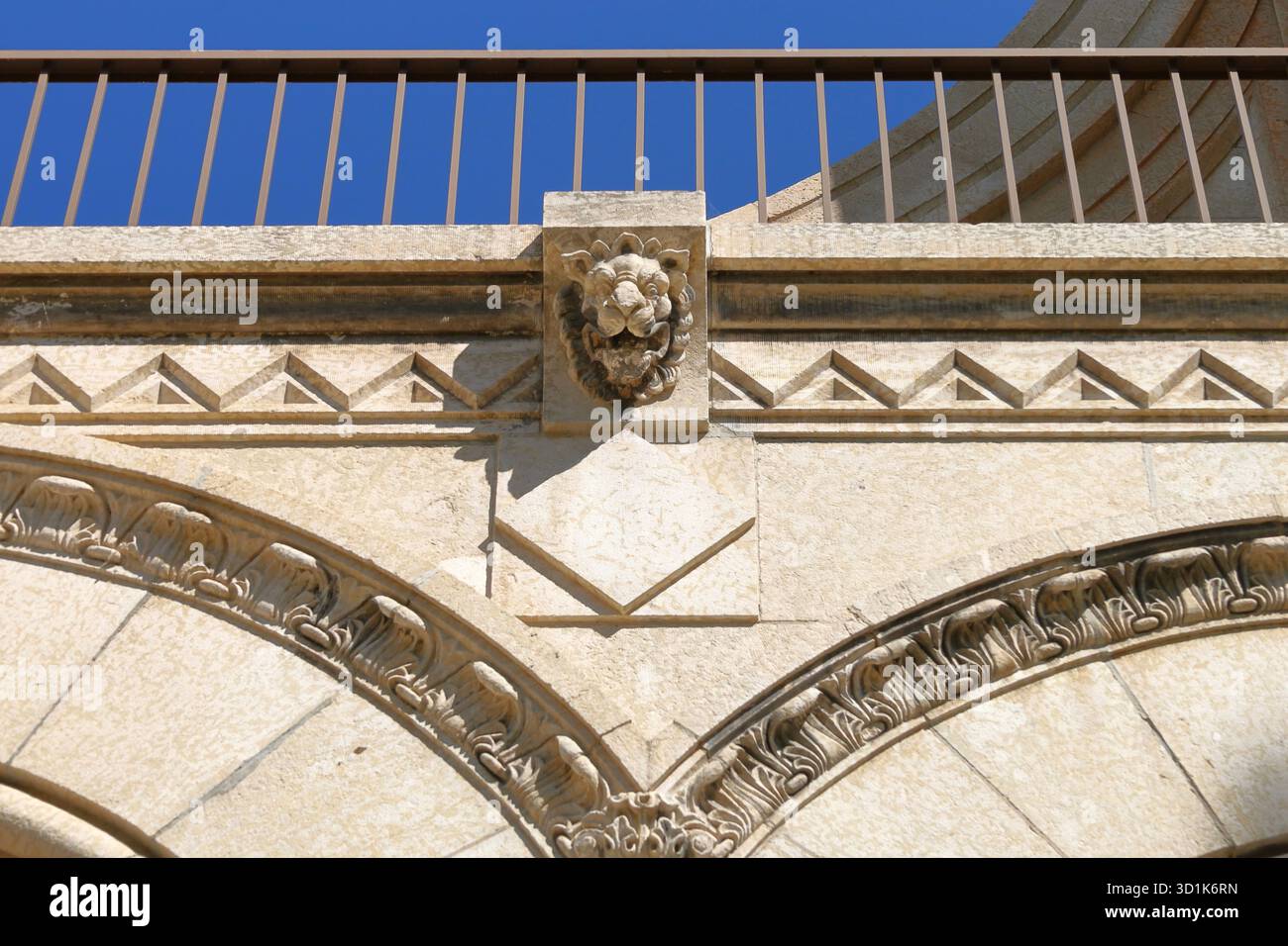 Historische Steinbögen mit verzierten Details. Elegante historische Gebäudefassade mit Steinbögen, dekorativen Schnitzereien und klassischen architektonischen Elementen Stockfoto