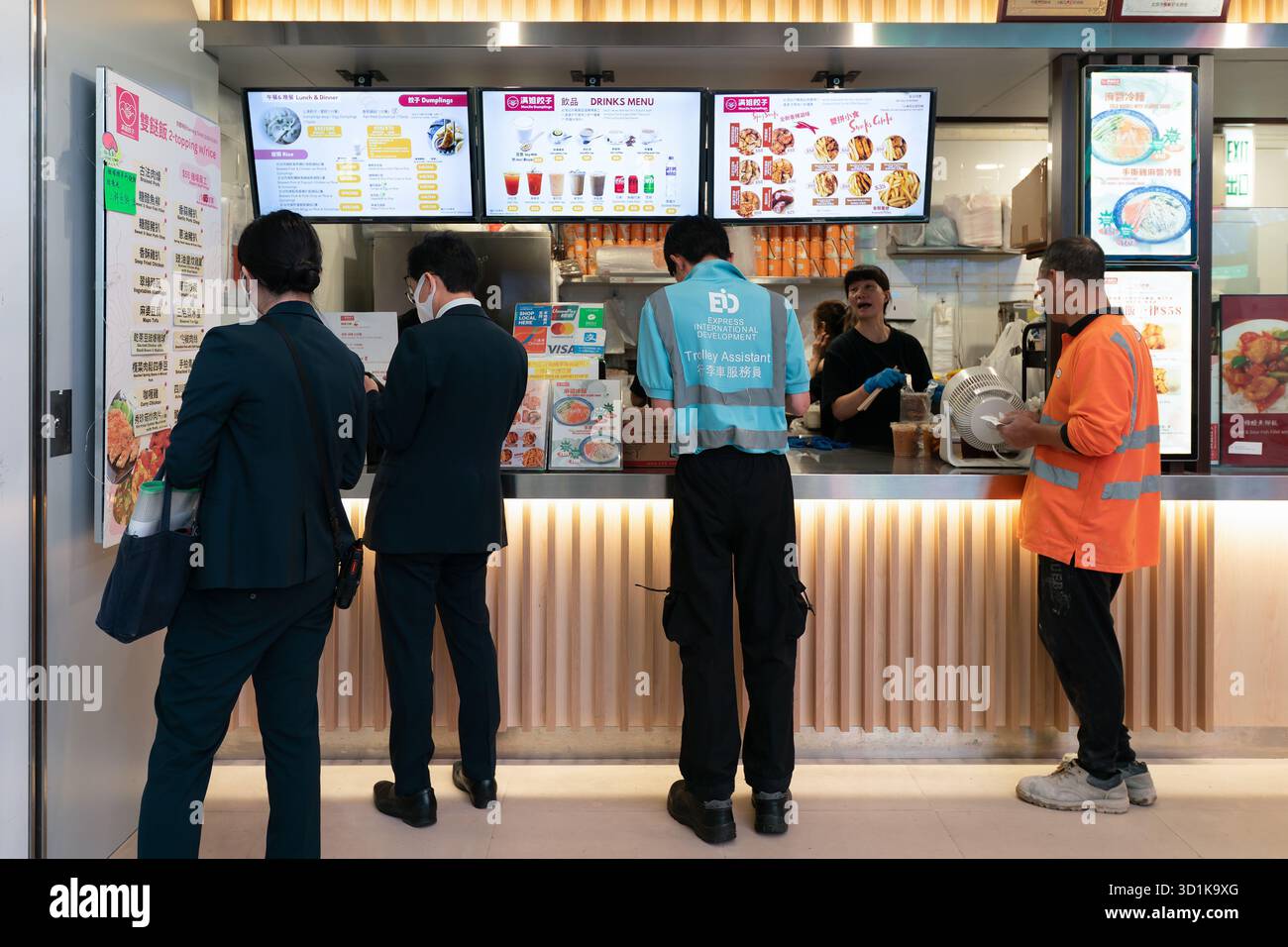 ong Kong, China - 20. September 2025: Kunden stehen am Serviceschalter von ManJie Dumplings, einem Restaurant im Pekinger Stil im Hong Kong International Stockfoto