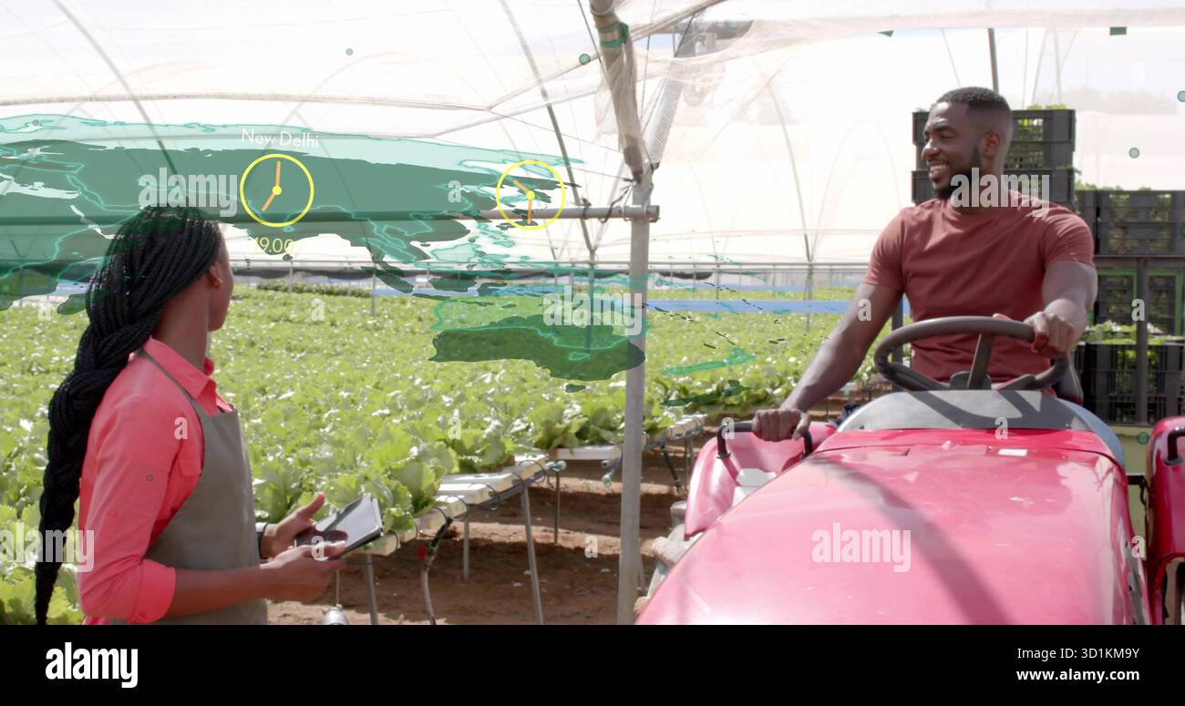 Gesten des Mitarbeiters mit Tablet neben dem Techniker, der den Traktor im Gewächshaus bedient, mit Salatbetten Stockfoto
