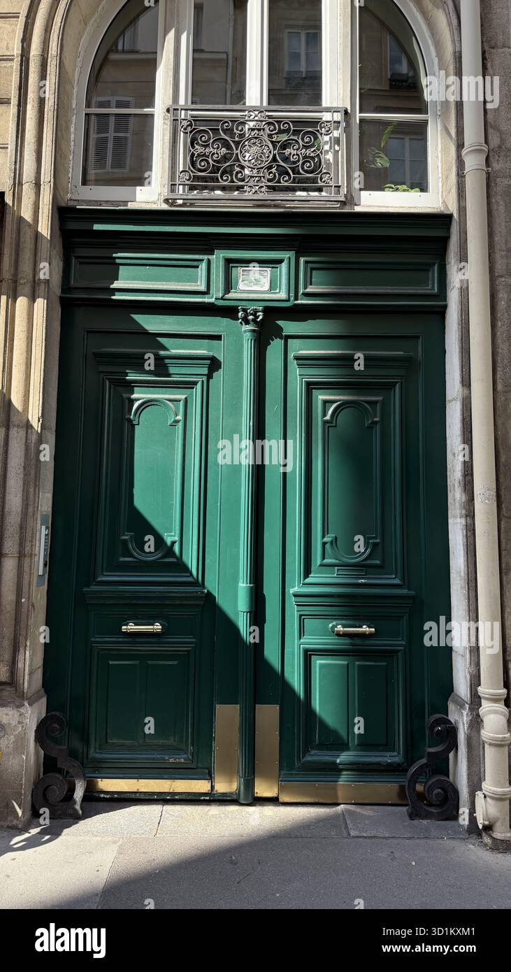 Beeindruckende grüne Doppeltür mit elegantem dekorativem Eisen und goldenen Akzenten. Mit aufwändiger Verkleidung und einem Bogenfenster, das klassisches A zeigt Stockfoto