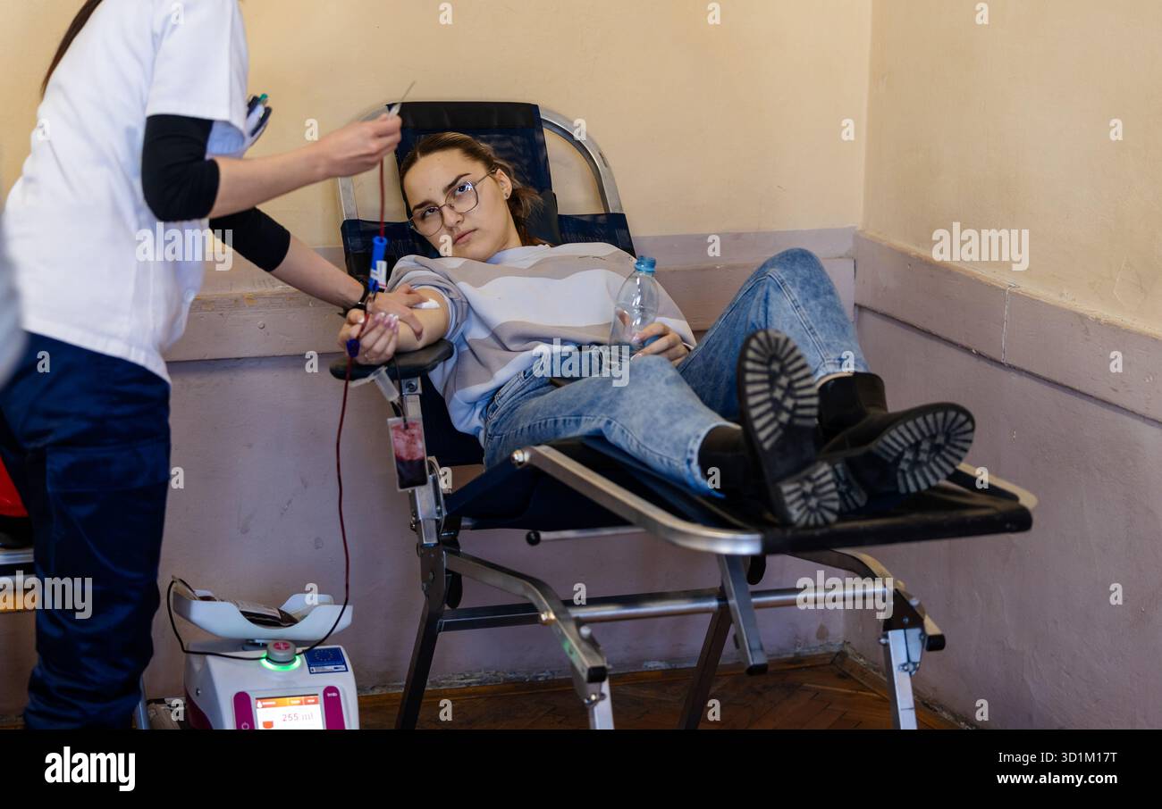 Die Frau sitzt, als die Krankenschwester während der Spendenfahrt Blut sammelt. Die Umgebung ist ruhig und organisiert und unterstreicht die Bemühungen der Gemeinschaft Stockfoto