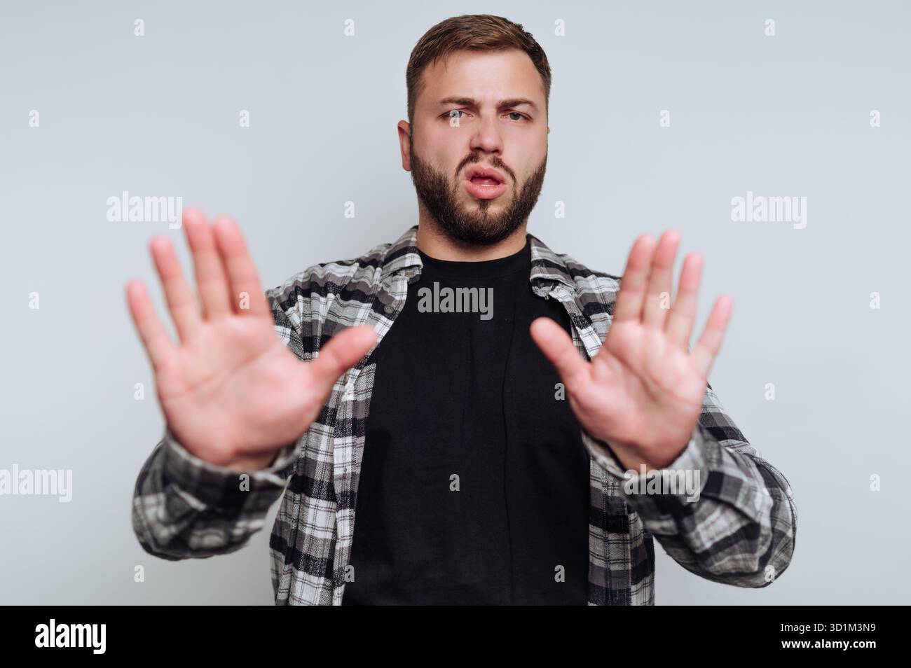 Mann in kariertem Hemd, der mit beiden Händen eine Stop-Geste macht. Stockfoto