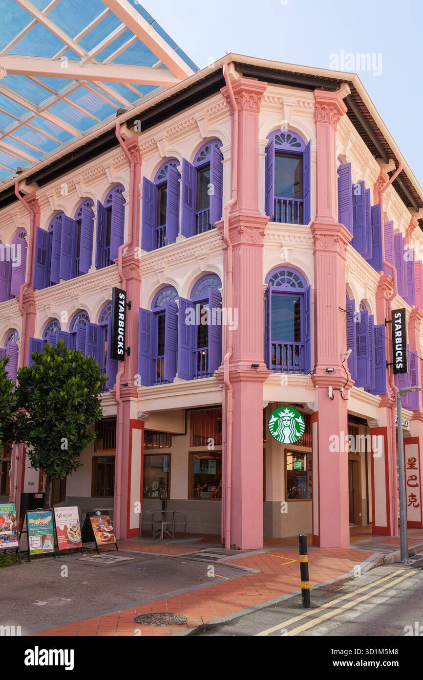 Ein denkmalgeschütztes Gebäude mit Starbucks-Farben in Pink und Lila und detaillierter Architektur. Die Leute laufen in der Nähe und genießen Cafés und Geschäfte Stockfoto