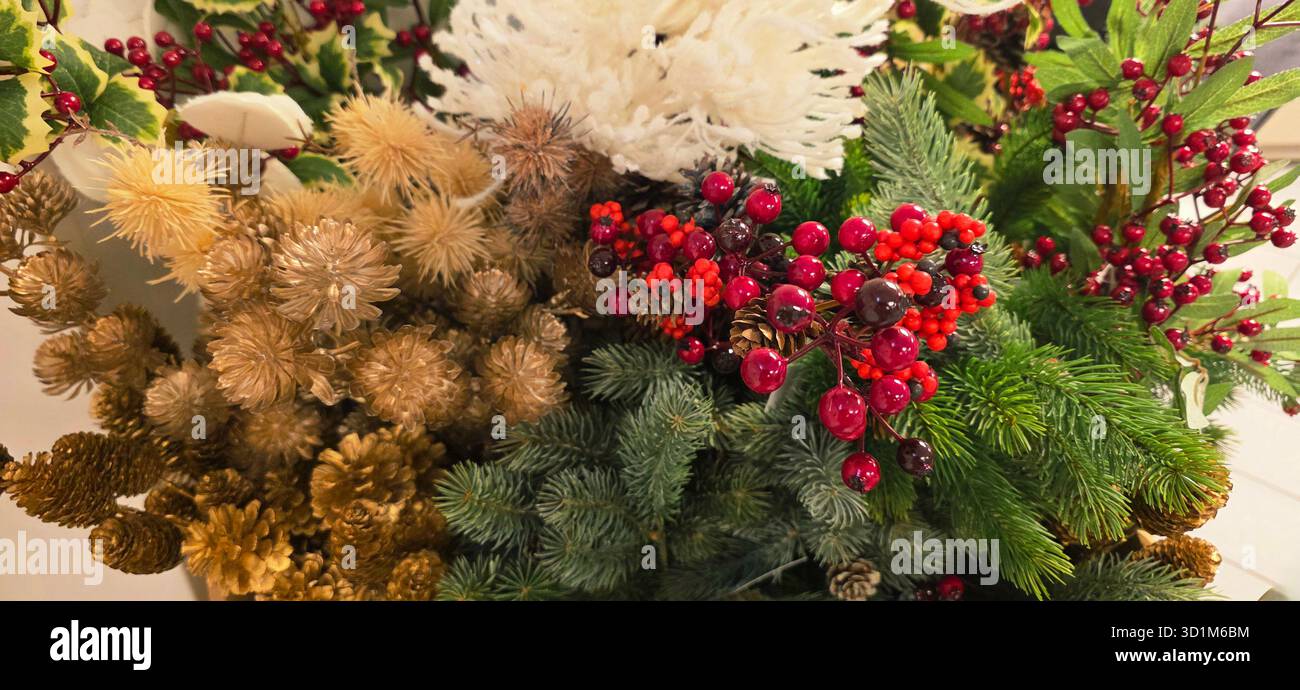 Das festliche Blumenarrangement mit saisonalem Laub, leuchtenden Beeren und dekorativen Elementen sorgt für eine warme und einladende Atmosphäre zum Feiern - Smartphone-aufgenommenes Stockfoto