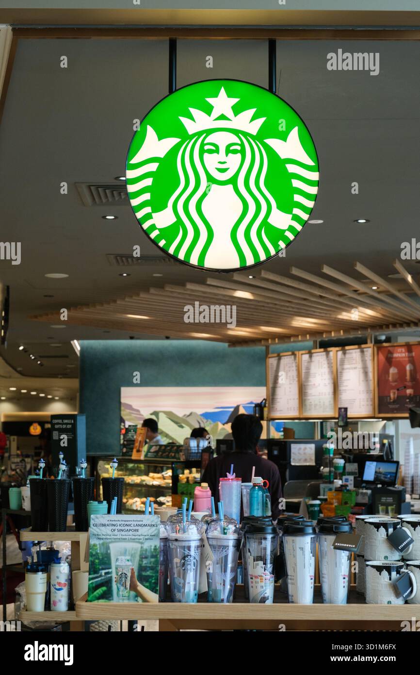 Das Starbucks-Geschäft am Flughafen Changi verfügt über ein grünes Logo, Holzakzente und zwanglose Sitzgelegenheiten. Die Menschen genießen Drinks in einer modernen Umgebung. Stockfoto