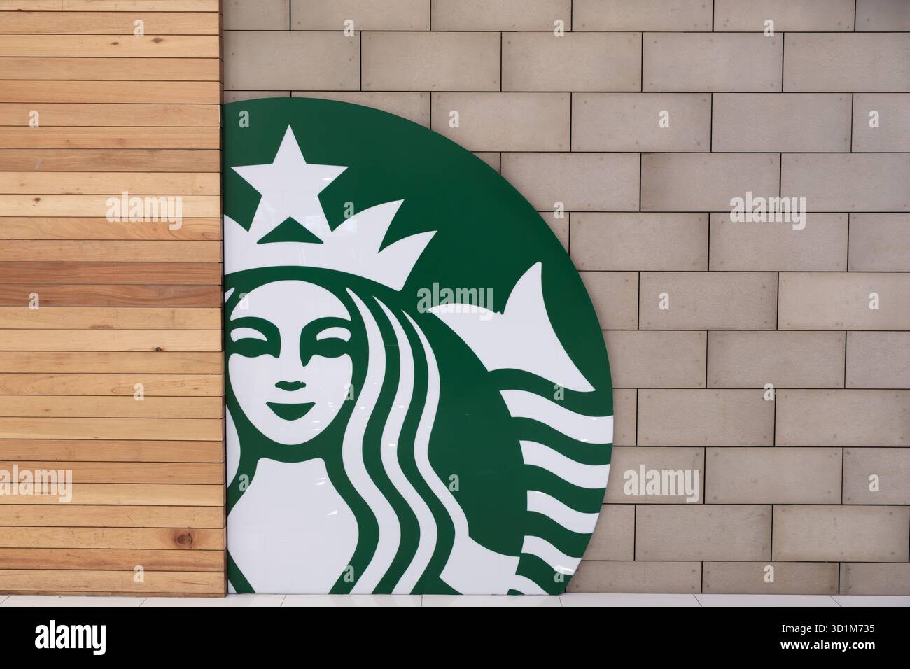 Penang, Malaysia – 16. Oktober 2025: Ein großes grünes Starbucks-Logo ist an einer Holzwand sichtbar, mit glattem Finish und weißem Detailin Stockfoto