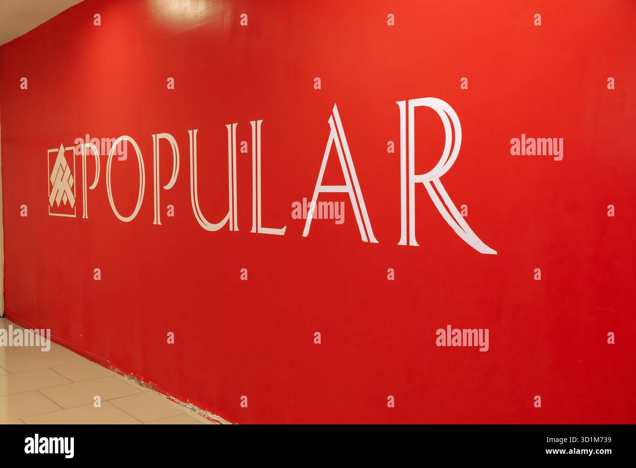 Die hellrote Wand zeigt das beliebte Logo in weiß. Die Umgebung ist gut beleuchtet, was die Sichtbarkeit und den Bekanntheitsgrad der Marke verbessert Stockfoto