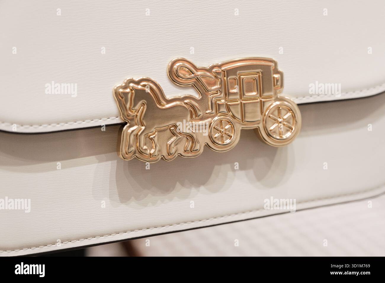 Eine luxuriöse Handtasche mit goldenem Pferd- und Kutschenlogo ist sichtbar. Die Tasche ist aus hochwertigem Leder gefertigt und zeigt Elega Stockfoto
