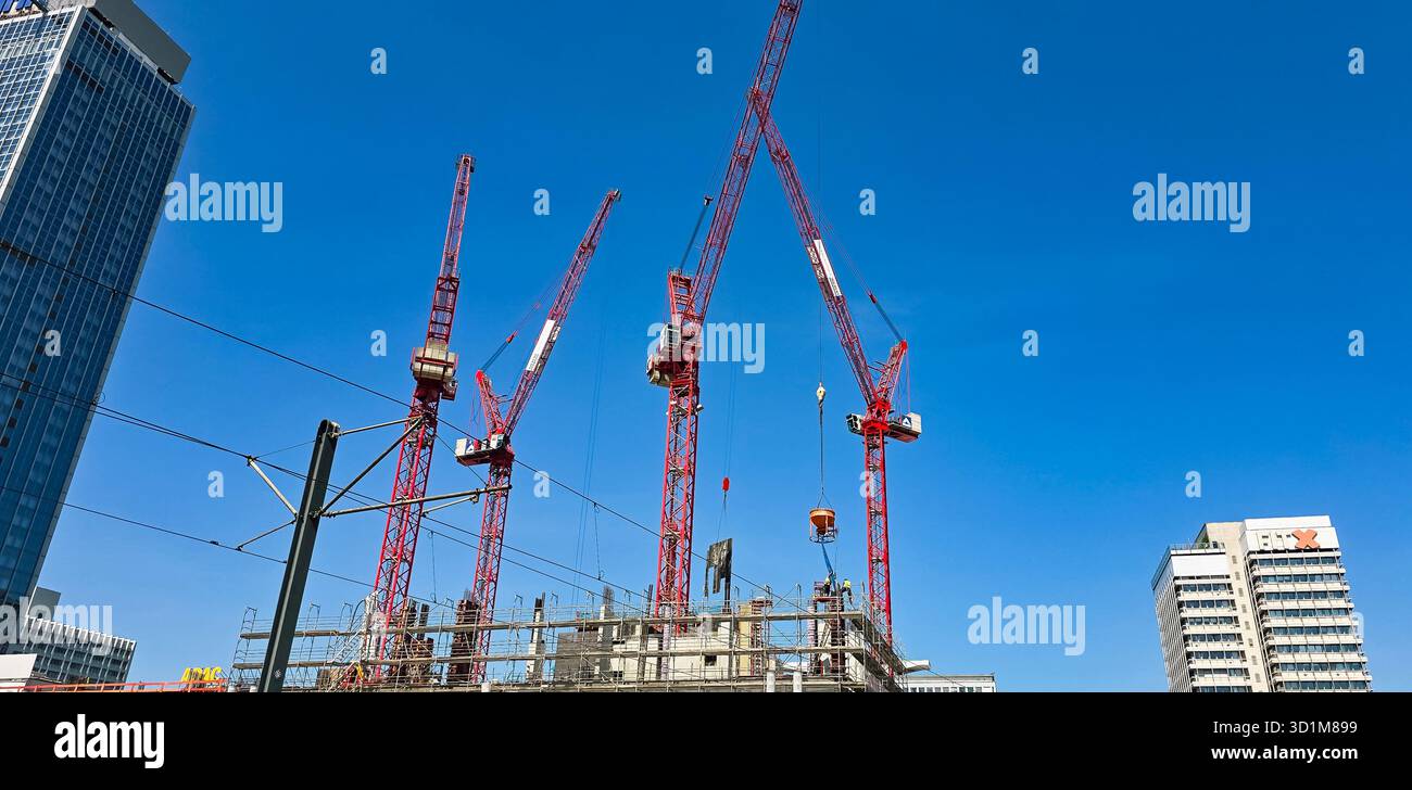 Berlin, Deutschland - 13. Juni 2025: Baukrane heben Materialien auf einer stark frequentierten städtischen Baustelle an. - Smartphone-aufgenommenes Stockfoto