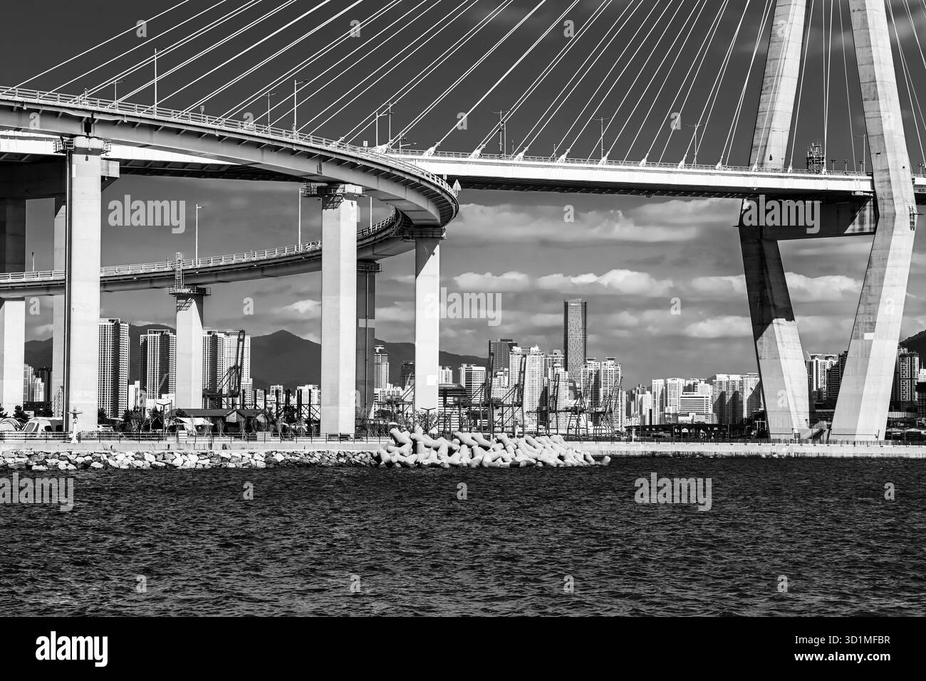 BUSAN, SÜDKOREA - 9. OKTOBER 2025 - Gwangan Brücke über die Bucht mit Busan Stadtgebäuden in Schwarz-weiß Stockfoto