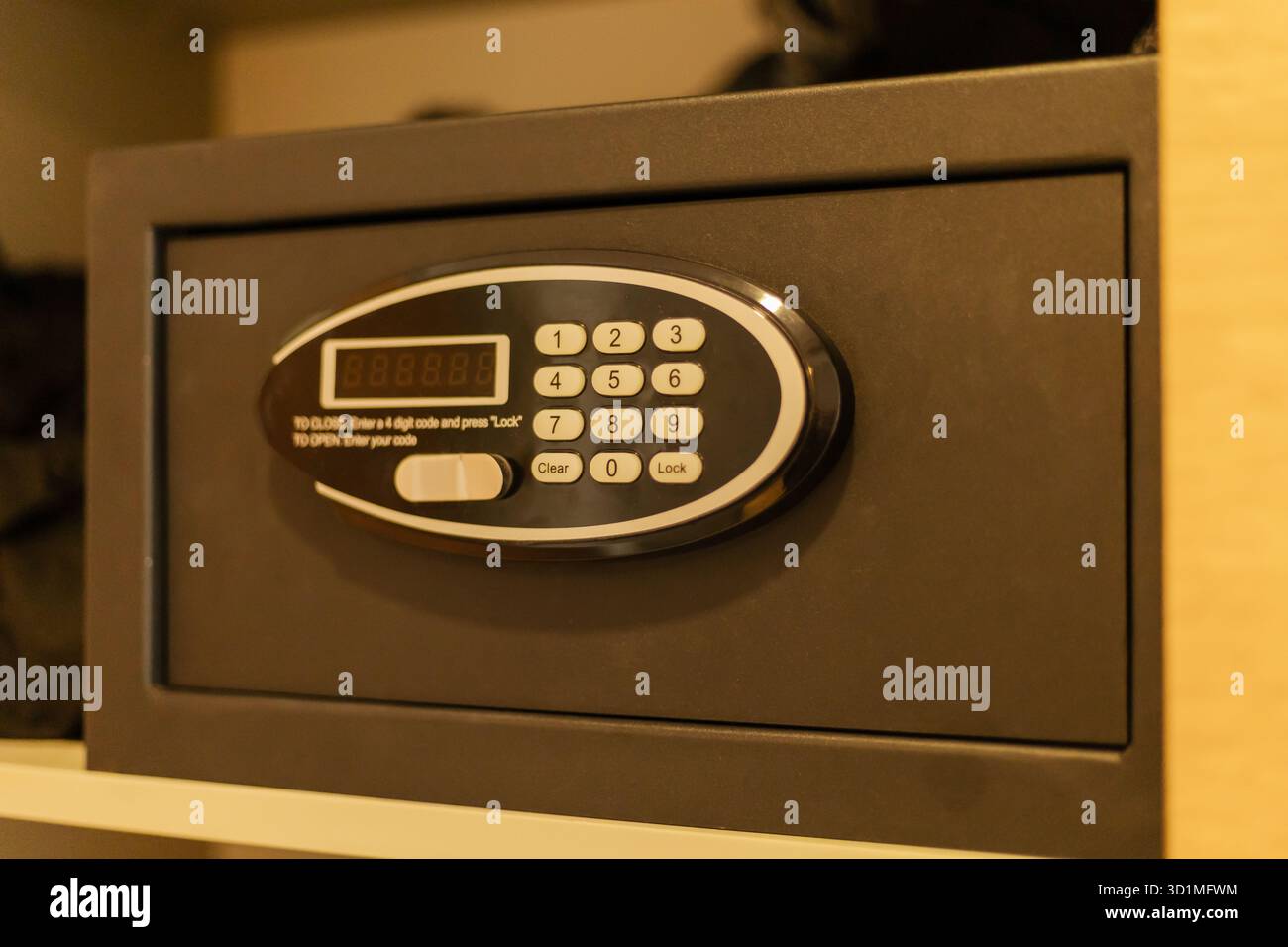 Ein digitaler Safe befindet sich in einem Holzschrank und ist mit einer Tastatur zur Eingabe eines eindeutigen Codes ausgestattet. Es bietet einen sicheren Ort für die Aufbewahrung von persönlichen Sachen i Stockfoto