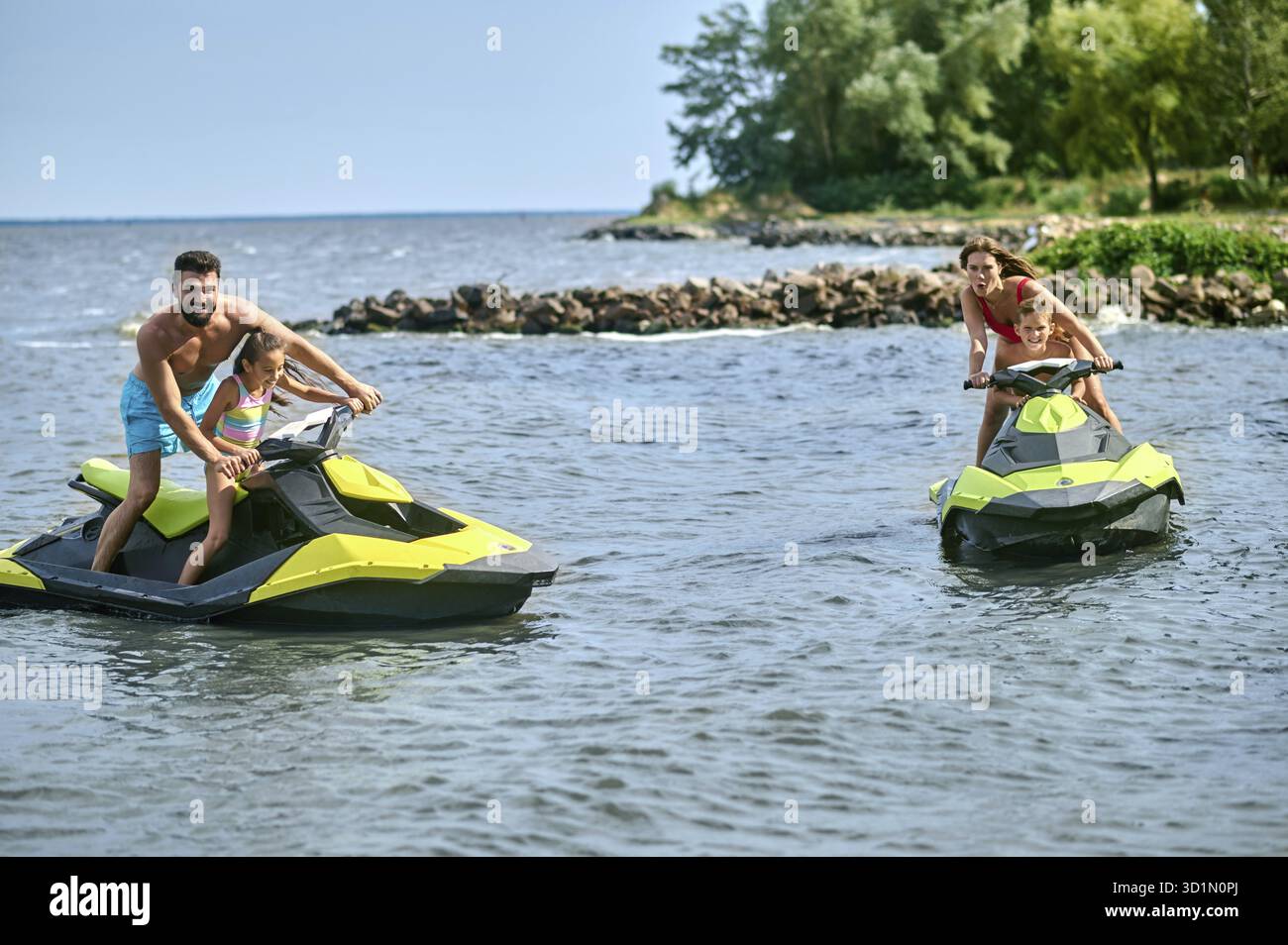 Vater, Mutter, Tochter und Sohn fahren auf Jetskis und genießen Wasserfahrzeuge im Meer, aktive Sommerzeit Stockfoto