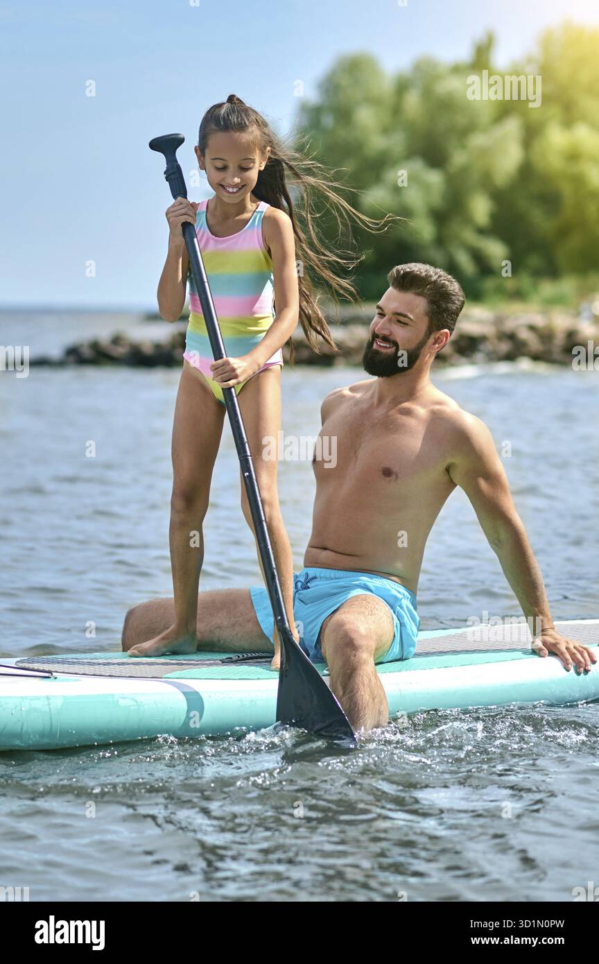 Aktive Freizeit. Vater und Tochter surfen auf Sup Board und haben lustige Zeit, Familienurlaub im Sommer Stockfoto