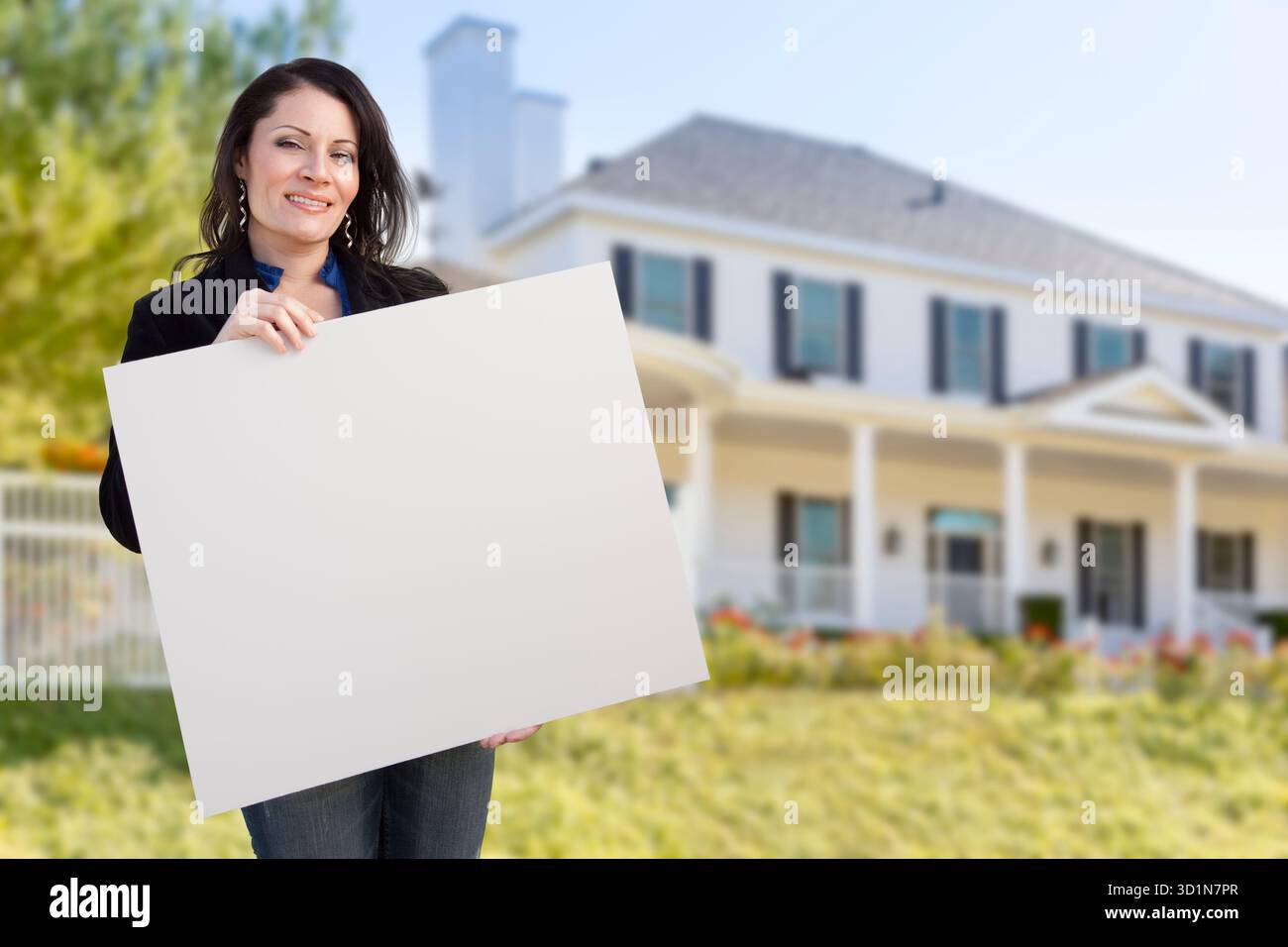 Hispanische Frau mit leerem Schild vor dem Haus Stockfoto