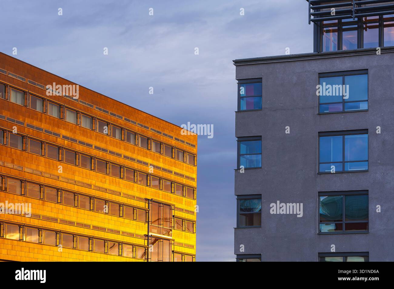 Goldenes Sonnenlicht beleuchtet die Glas- und Betonflächen von Bürogebäuden in Göteborg, Schweden, und schafft eine warme Atmosphäre bei Sonnenaufgang. Die Himmelsrichtung Stockfoto