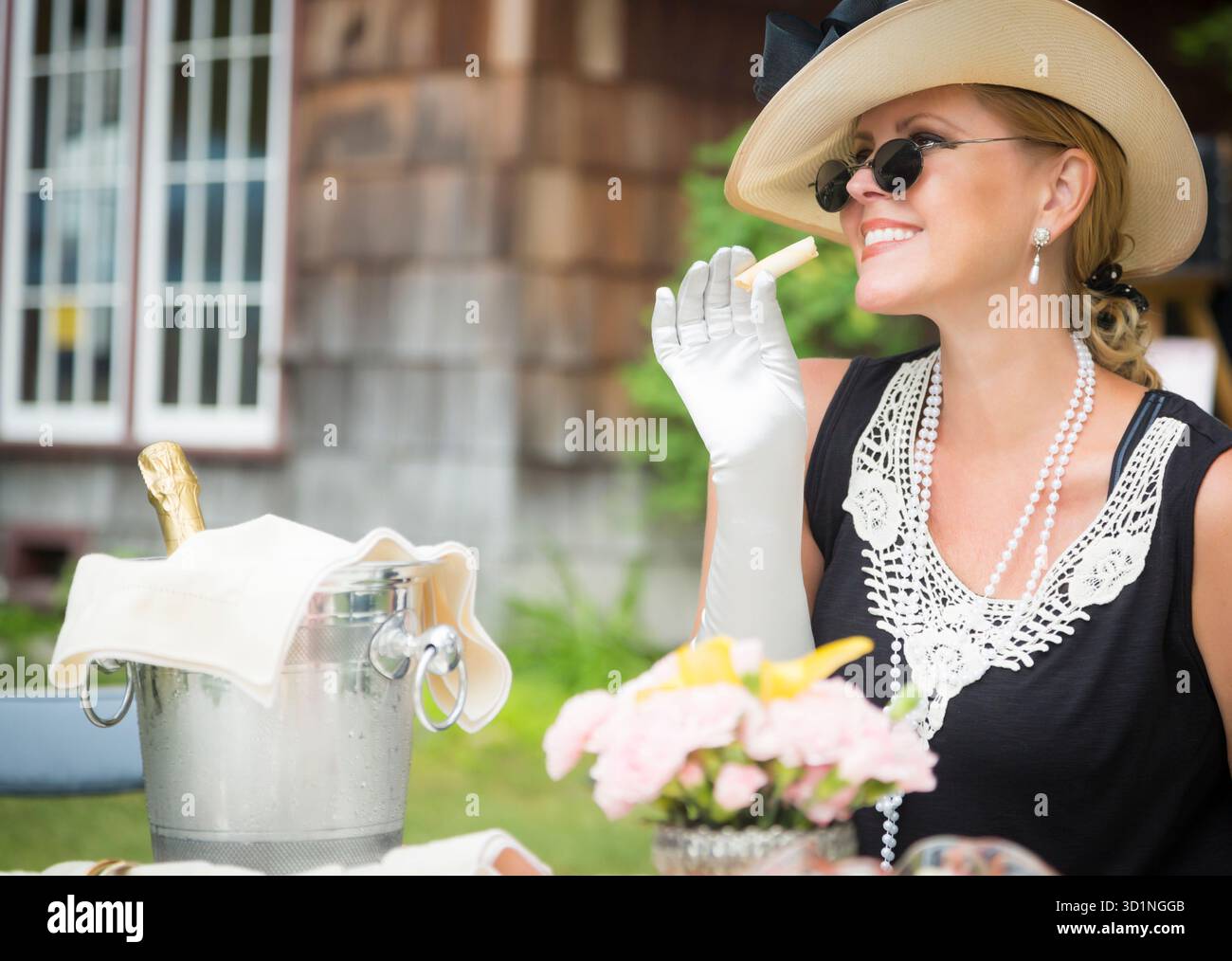 20er Jahre gekleidete Frau isst und trinkt Champagner auf der Outdoor Party Stockfoto