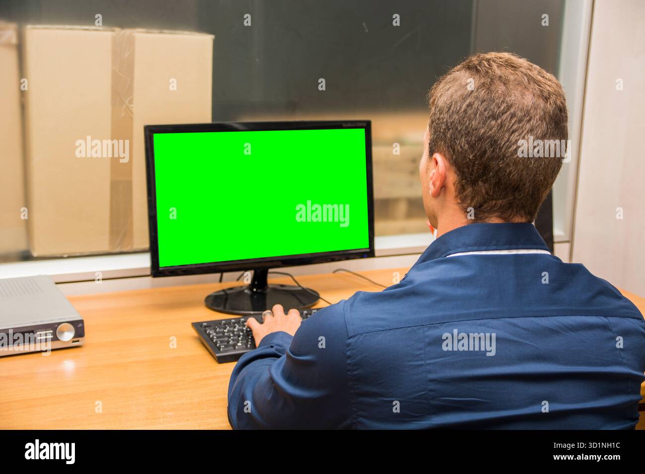 Junger männlicher Büroangestellter, der an seinem Schreibtisch sitzt und am Computer arbeitet Stockfoto