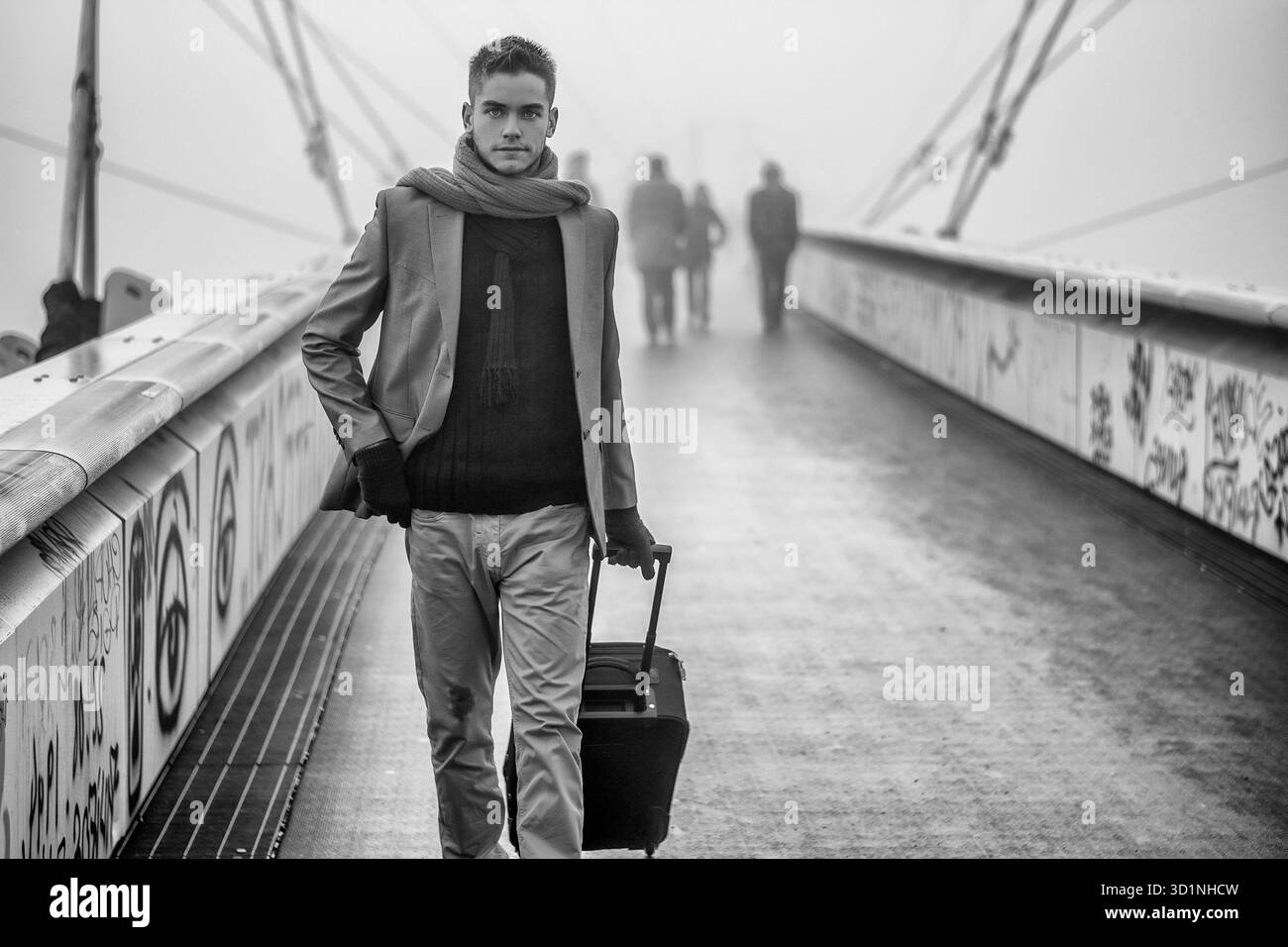 Trendiger, gutaussehender Mann, der mit einem Koffer läuft Stockfoto