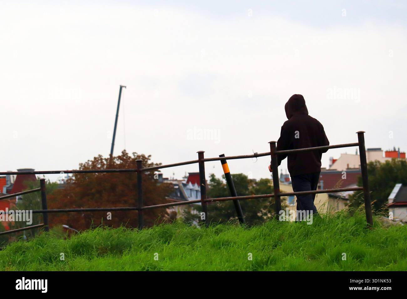 Ein Mann in einer Kapuze spaziert an einem Herbstabend in einer städtischen Umgebung Stockfoto