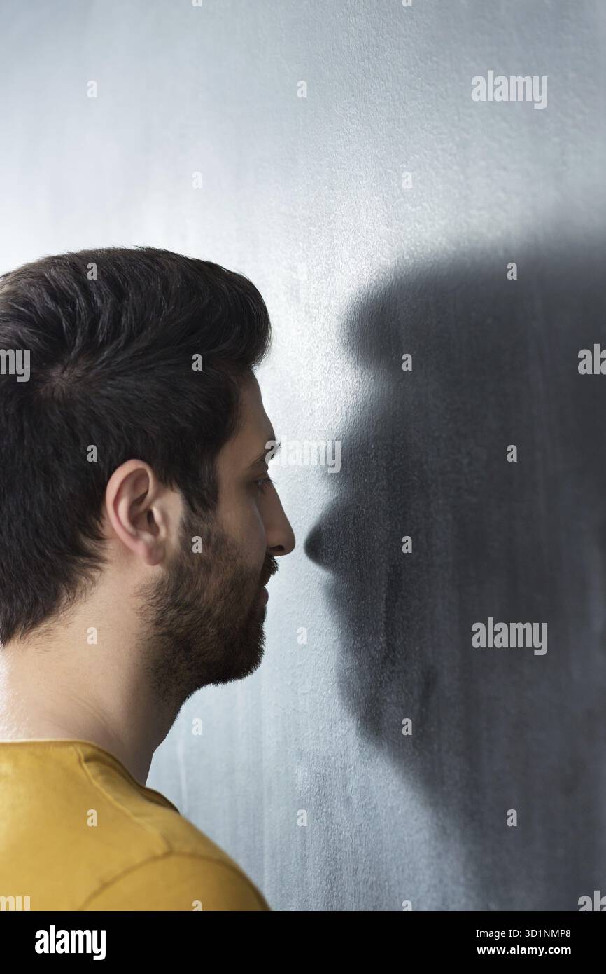 Studio-Porträt eines kaukasischen erwachsenen Mannes in seinen frühen 30ern über grauem Hintergrund. Er scheint gut gelaunt zu sein und sieht auch mit einem großen in die Kamera Stockfoto