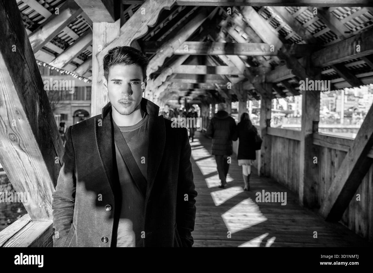 Junger Mann, der auf einer hölzernen Fußgängerbrücke in der Schweiz steht und wegschaut Stockfoto