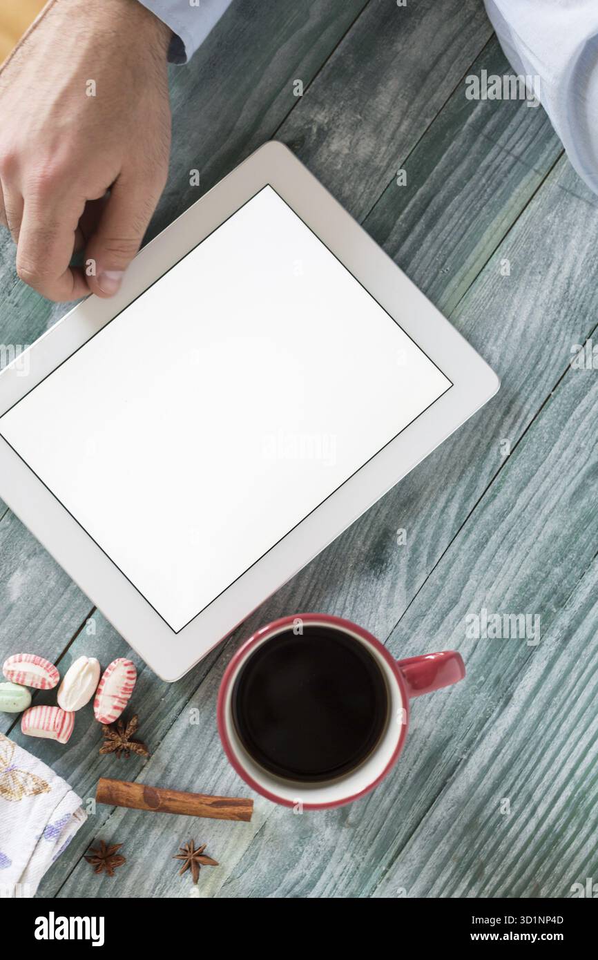 Hand mit Mockup Tablet ähnlich dem ipad-Stil auf Holzschreibtisch weißes Display mit Beschneidungspfad Bildschirm einfaches Hinzufügen von Bild Stockfoto