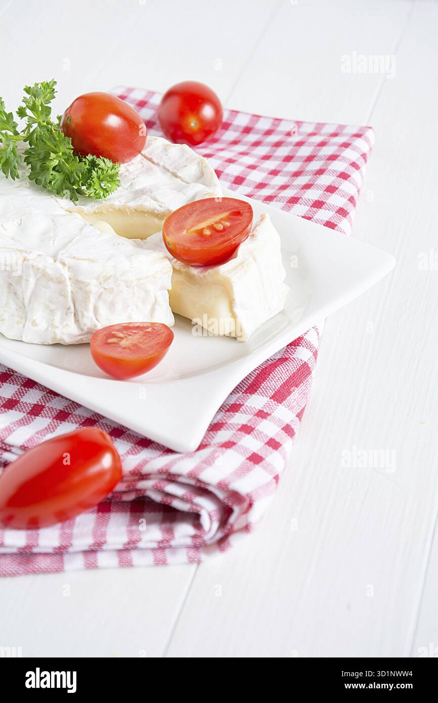 Ein runder Camenbert mit Cocktailtomaten auf einem Teller Stockfoto