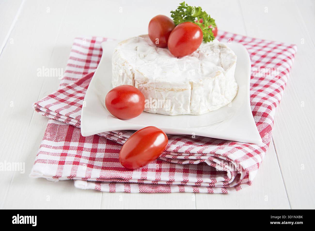 Ein runder Camenbert mit Cocktailtomaten auf einem Teller Stockfoto