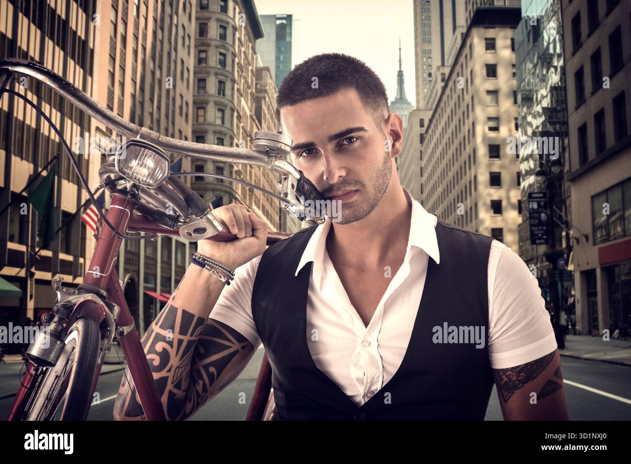 Tätowierter, eleganter Mann, der sein Fahrrad hält Stockfoto