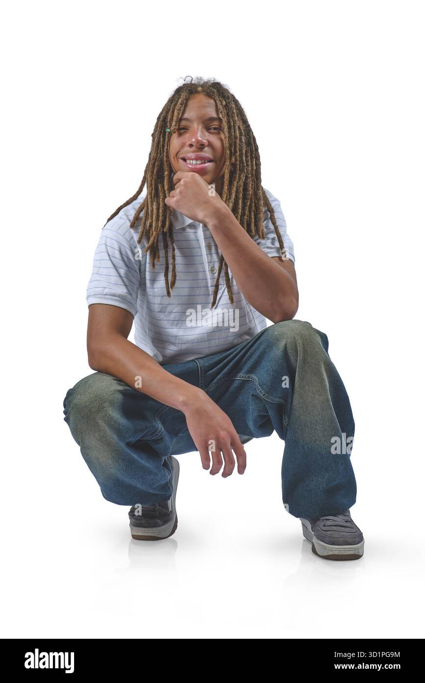 Junger Mann mit Dreadlocks, die sich hocken und nachdenklich auf weißem Hintergrund erscheinen Stockfoto