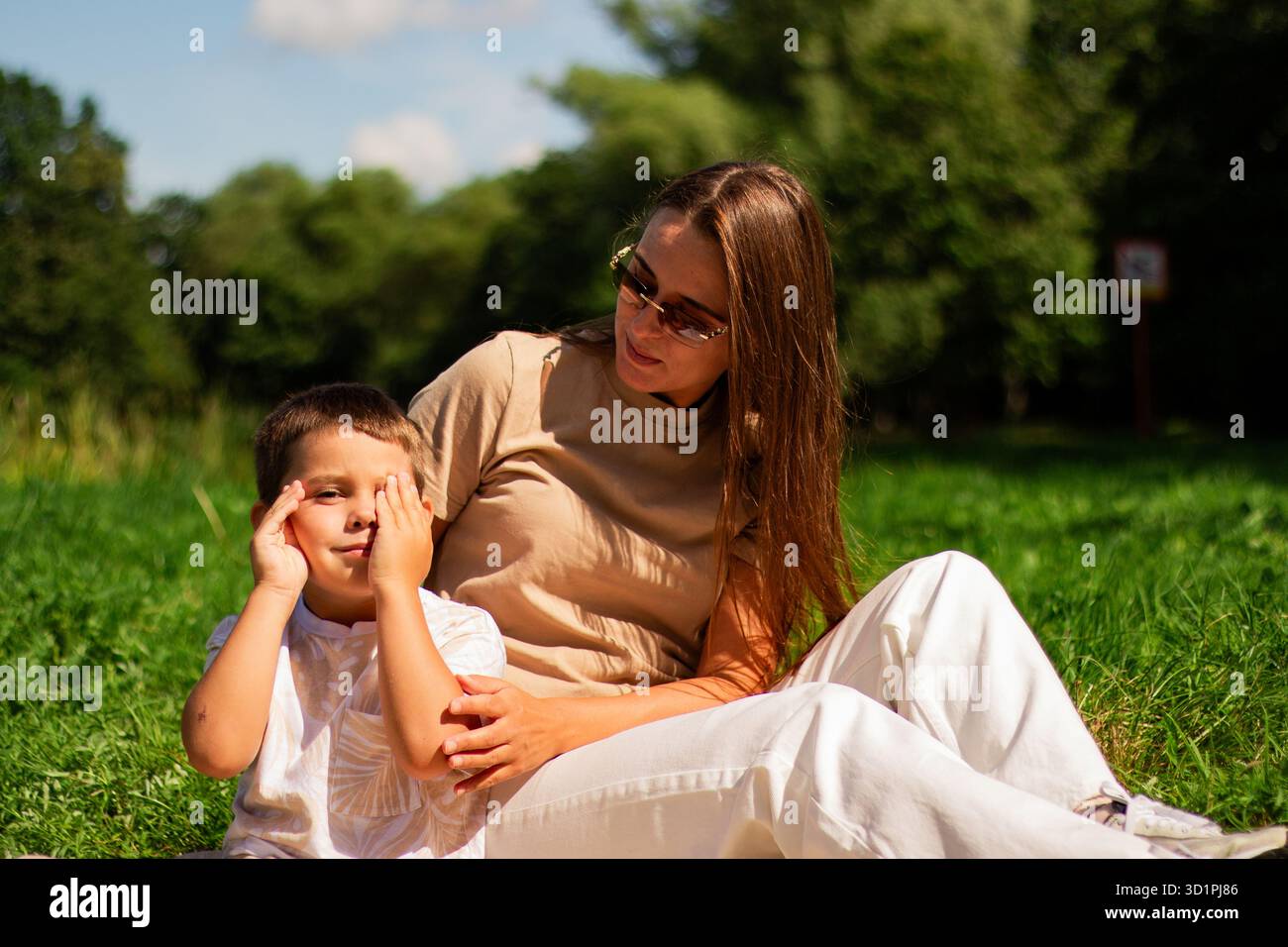 Mutter mit Kind, die Spaß im öffentlichen grünen Park hat. Glückliche Mutter lacht zusammen mit dem Sohn. Hochwertige Freizeit im Freien. Stockfoto