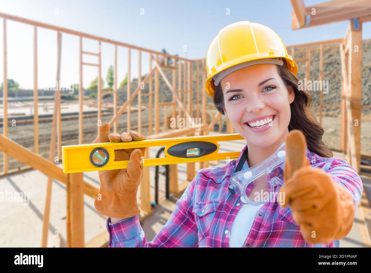 Bauarbeiterin mit den Daumen nach oben, tragende Handschuhe, Schutzhelm und Schutzbrille auf der Baustelle Stockfoto