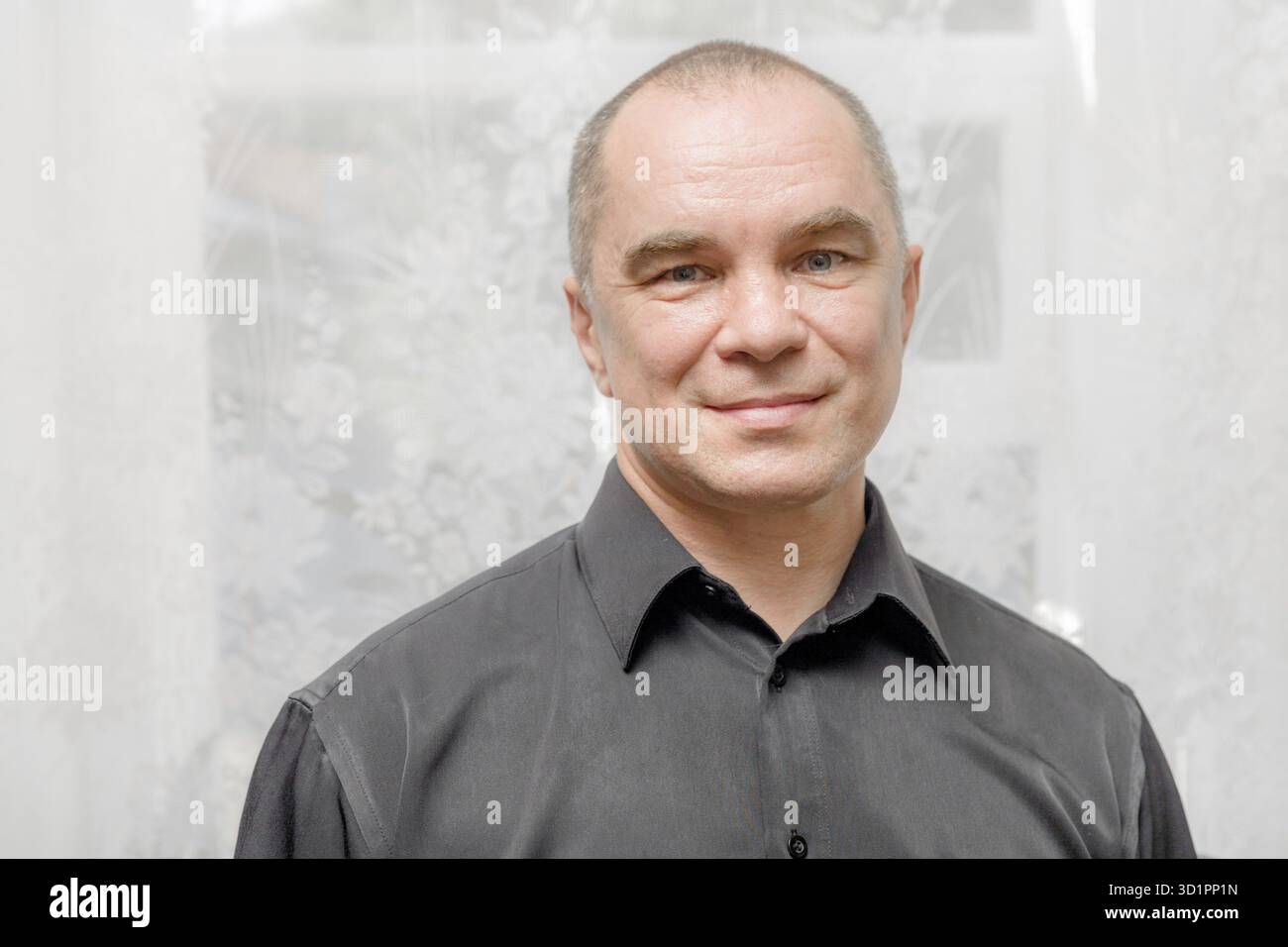 Schöner kaukasischer Mann aus den 40er Jahren lächelndes Porträt auf grauem Hintergrund mit schwarzem Hemd Stockfoto