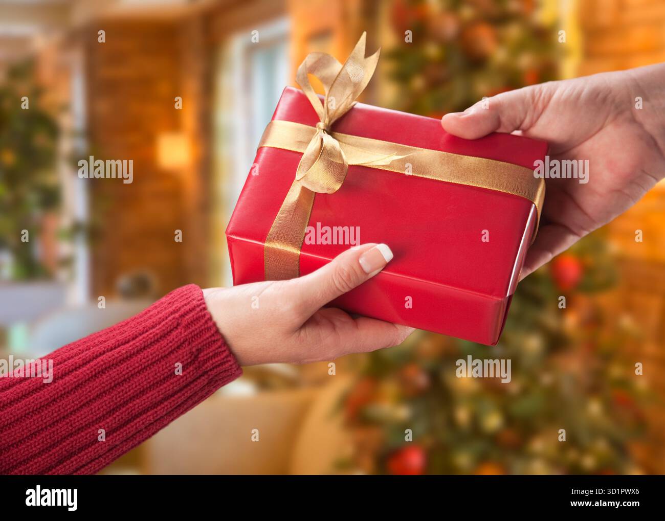 Mann und Frau Geschenkantausch vor dem geschmückten Weihnachtsbaum. Stockfoto