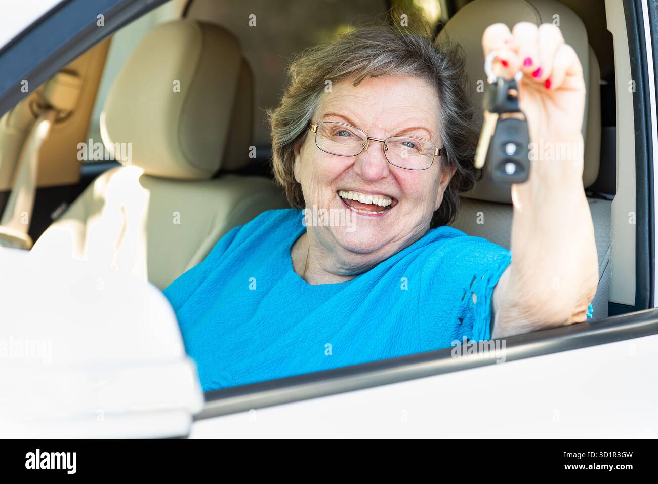 Glückliche Seniorin, Die Im Neuwagen Sitzt Und Die Schlüssel Hält Stockfoto