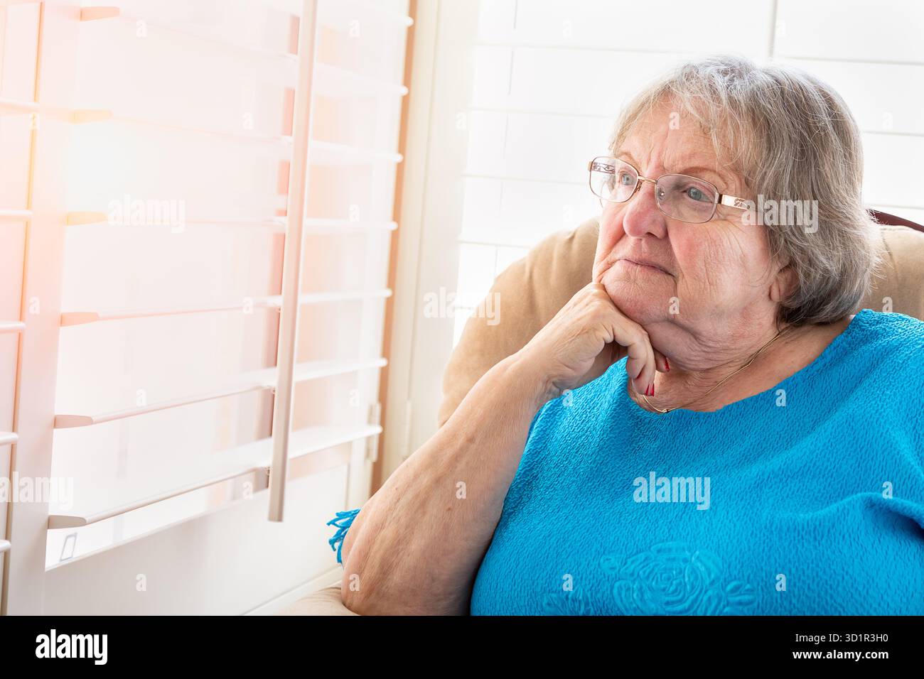 Besinnliche Seniorin, die aus ihrem Fenster blickt Stockfoto