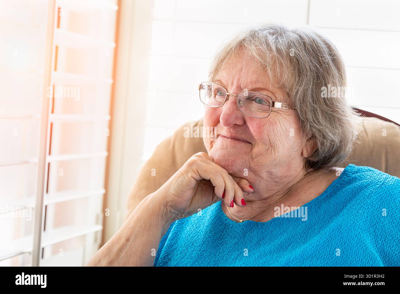Zufriedene Seniorin, die aus ihrem Fenster blickt Stockfoto