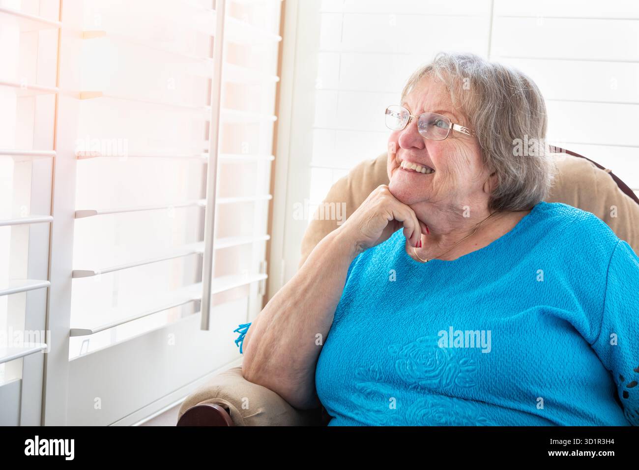 Zufriedene Seniorin, die aus ihrem Fenster blickt Stockfoto