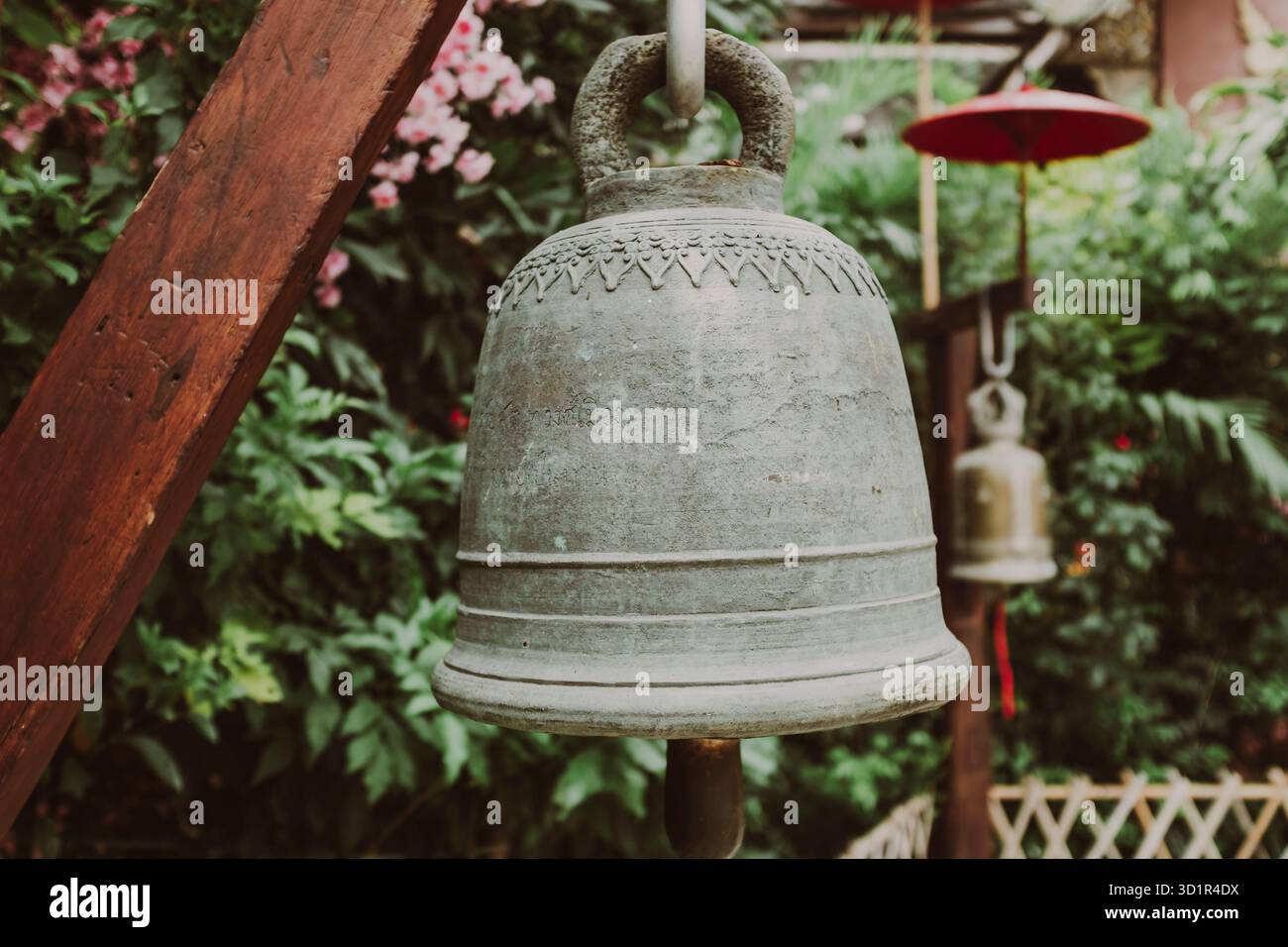 Alte Eisenglocke in einem traditionellen Garten in einem buddhistischen Tempel in Chiang Rai, Thailand Stockfoto