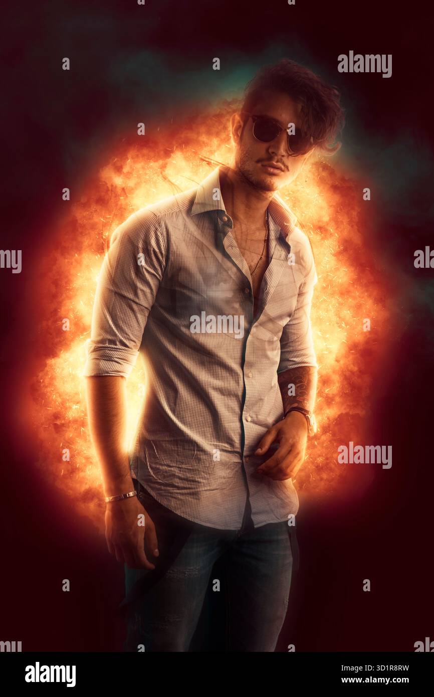 Hübscher junger Mann gegen flame Burst stehen Stockfoto
