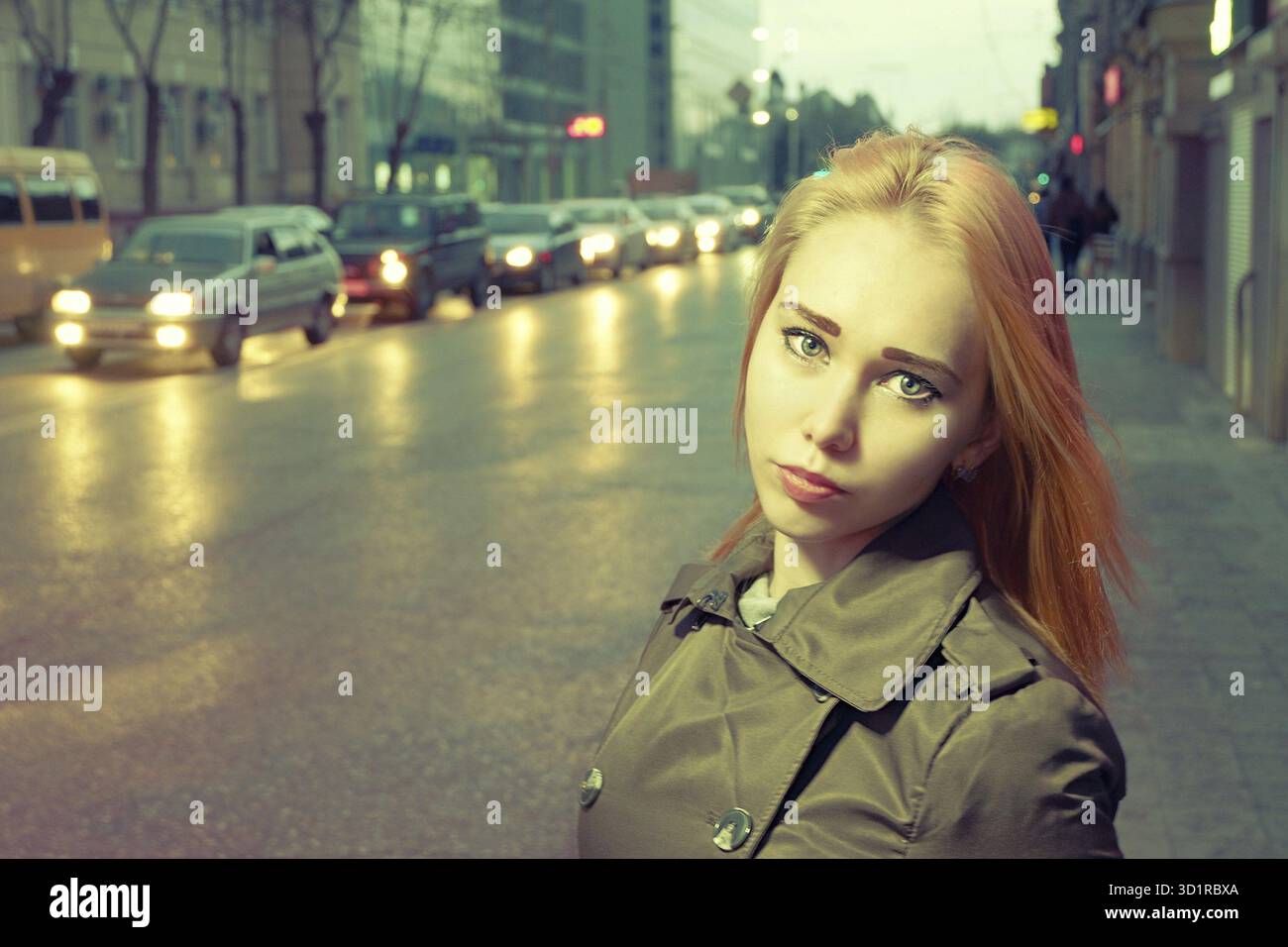 Hübsches Mädchen in der Nachtstadt auf der Straße. Stadtlichter und Karllichter sind im Hintergrund unscharf. Vintage-Farbe Stockfoto