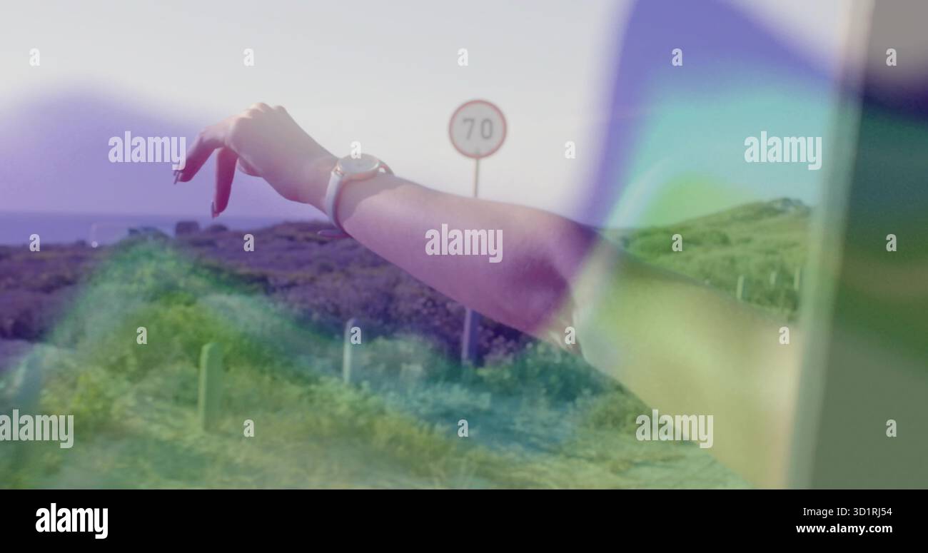 Den Arm der Frau aus dem Fenster zur Straße ausdehnen, mit roten Nägeln, silberner Armbanduhr, Geschwindigkeitsschild mit 70 Stockfoto