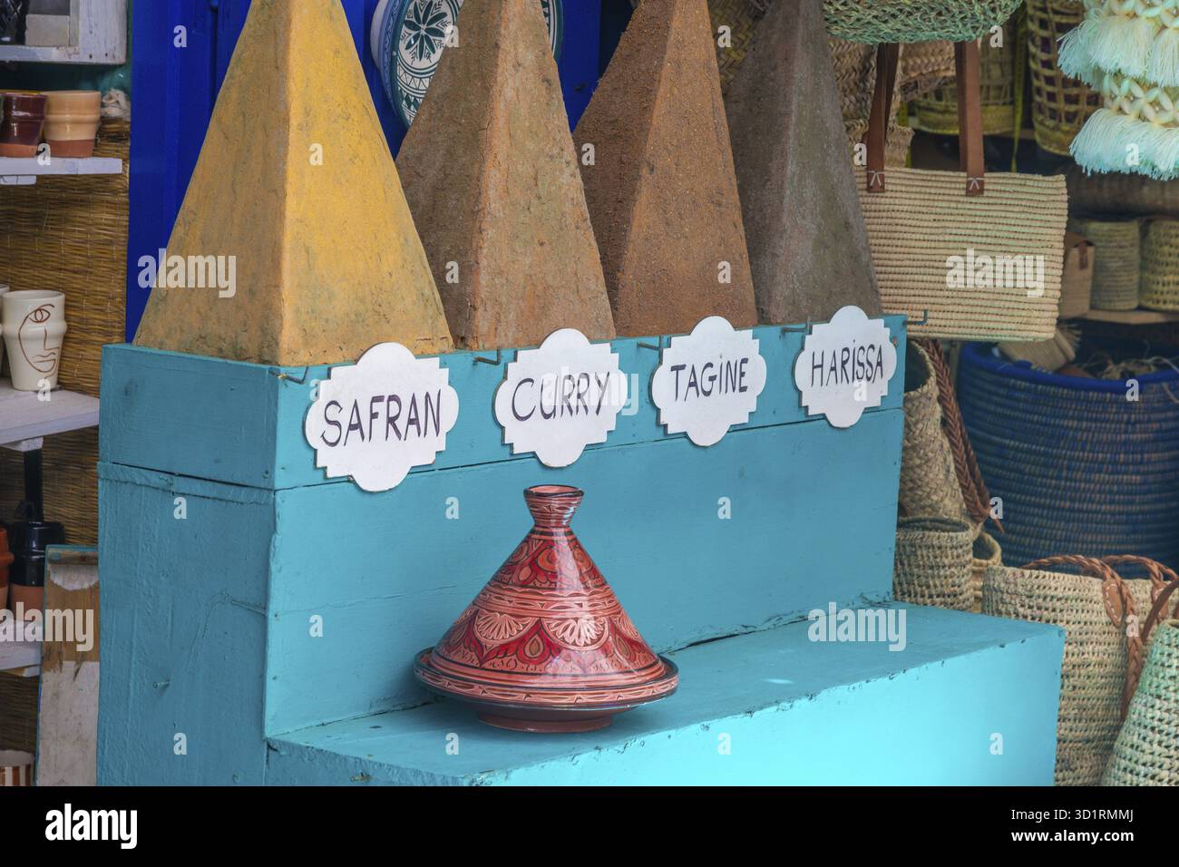 Cordoba, Cordoba - Spanien - 04-08-2024: Große Gewürzkegel wie Safran und Curry, dekorative Tajine auf einem blauen Regal im Basar Stockfoto