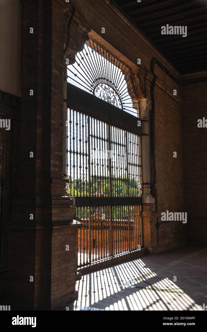 Sevilla, Sevilla - Spanien â€“ 19. 04. 2024: Sonnenlicht wirft komplizierte Schatten durch das Eisentor der Plaza de Espana und trägt zur architektonischen Verkleidung bei Stockfoto