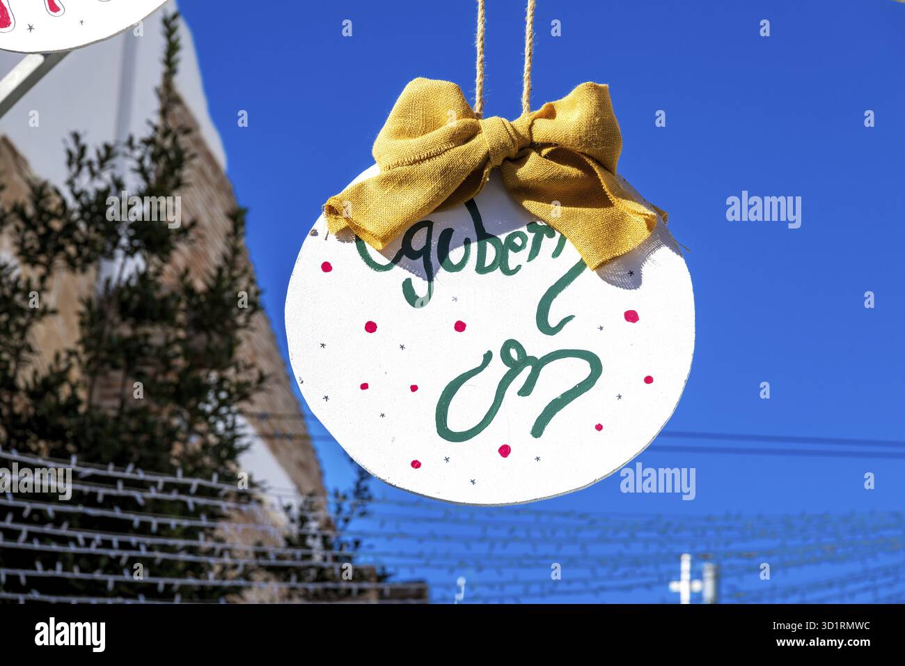 Denia, Alicante - Spanien - 22.12.2023: Hellblauer Himmel mit „Merry Christmas“-Schild und roter Schleife Stockfoto
