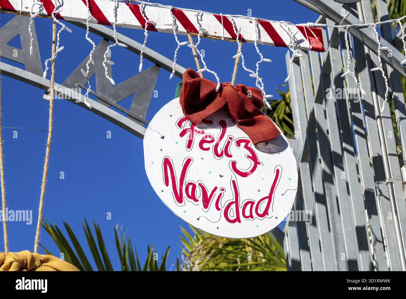 Denia, Alicante - Spanien - 22.12.2023: Hellblauer Himmel mit „Feliz Navidad“ Weihnachtsschild in spanischer Sprache und rotem Band Stockfoto